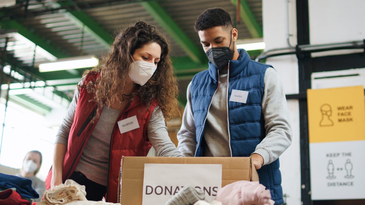 Group of volunteers working in community charity donation centre, coronavirus concept.