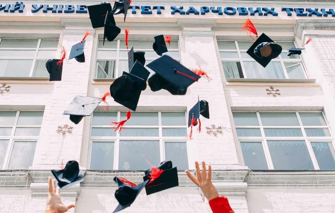 Graduates throwing graduation caps in air.